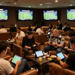 Dynamic scene of enthusiastic bettors engaging with live sports odds at keonhacaii88's premium betting lounge
